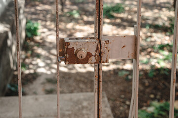 Detail of a lock on the old metal gate with peeling, rusty paint.