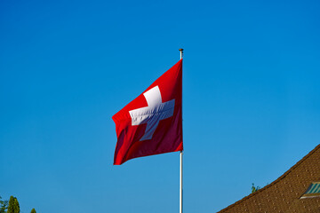 Waving Swiss flag at family home at City of Lenzburg on a sunny evening. Photo taken June 11th, 2023, Lenzburg, Switzerland.