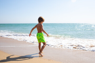 Cute little boy playing on the beach on summer holidays. Joyful child in nature with beautiful sea,...