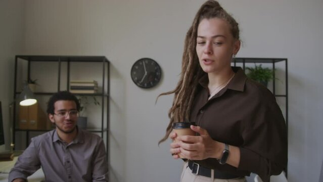 Tilting medium shot of young Caucasian woman demonstrating software HTML code on computer screen to Biracial male colleague in office