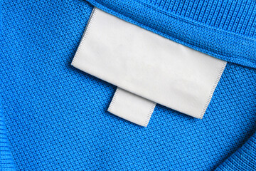 Blank white laundry care clothes label on blue shirt fabric texture background