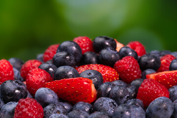 Close-up of juicy blueberries, strawberries, raspberries on a green blurred background. Colorful background of berries, summer food.