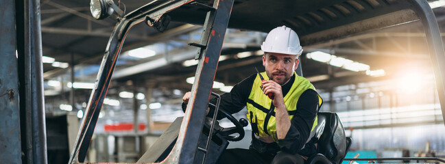 Industrial worker driving a forklift in the factory. Engineer is working and maintaining in the...