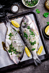 Grilled dorado with herbs on a platter and baked potatoes..style rustic