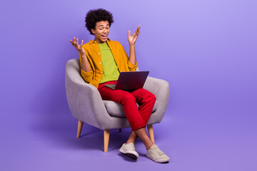 Fototapeta na wymiar Photo of excited cheerful positive nice man sitting in armchair speaking video call meeting isolated on purple color background