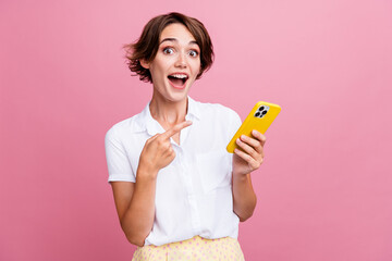 Photo of ecstatic impressed girl with bob hairdo dressed white shirt directing at smartphone staring isolated on pink color background - obrazy, fototapety, plakaty
