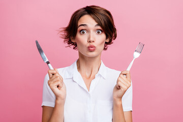 Portrait of funny young girl pouty lips hold fork with knife in restaurant waiting her delicious...