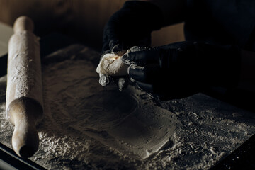 Hand in black gloves delicately shaping dough, showcasing meticulous culinary skill and care in food preparation