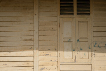 A wooden structure wall and window of an old village house shows the contrast of shadow under the afternoon sunshine in a small town in Perak, Malaysia. 