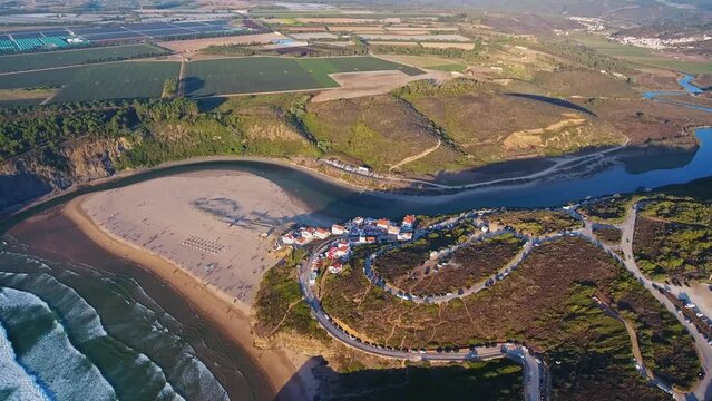Aerial video filming by drone of the sea bay and beach near the village of Odeceixe Alentejo Portugal. During sunset, birds eye view of the village.