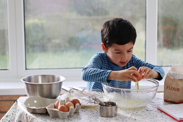 Child broke fresh egg. Child hand crack egg for cooking, baking cake, waffles at home in the...