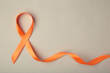 Orange ribbon on grey background . Healthcare and medicine concept. Multiple Sclerosis awareness. Leukemia awareness. Empty text space