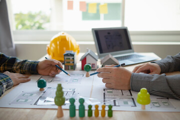 Construction engineers discuss and exchange ideas with architects to improve house plans to meet...