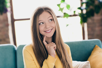 Photo of satisfied good mood girl with straight hairdo dressed yellow pullover finger on cheek thoughtfully dreaming inside indoors