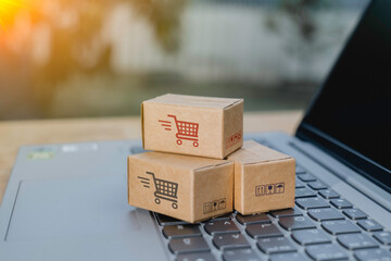 Paper cartons or parcel with shopping cart logo on laptop keyboard for online shopping or ecommerce and delivery service concept. Shopping service online and offer home delivery via the internet.