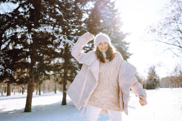 Happy woman walking on a snowy winter day outdoors. Beautiful woman having fun with snow in a snowy park. Walking concept.