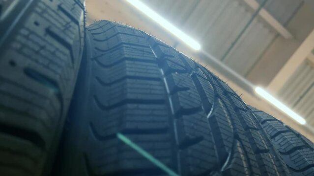 New winter car tires lined up on the shelf at the auto store. Close up shot