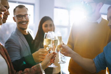 Colleagues in the office celebrate the concluded deal with champagne and sparkling wine. A group of people with glasses of champagne having fun, relaxing in the office. Concept of work, holiday.