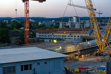 Mobile crane lifting and placing girder at highway enclosure construction site at City of Zürich...