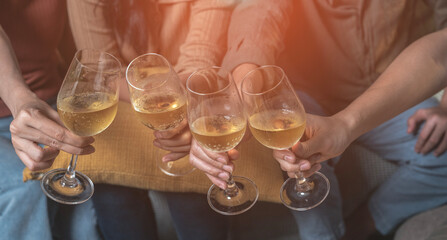 White wine glasses clinking together, friends celebrating a new year's birthday, partying together,...