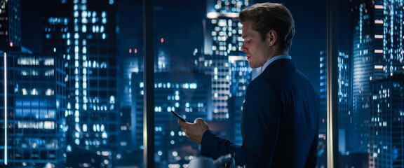 Sideview of Handsome Caucasian Businessman in Stylish Suit Standing Next to Window in Big City...