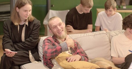 Bearded man in a group of students. Sitting on the sofa in a positive mood. Adaptation to the working mode.