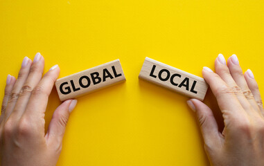 Global and Local symbol. Concept word Global and Local on wooden blocks. Businessman hand. Beautiful yellow background. Business and Global and Local concept. Copy space