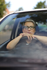 A frustrated mature woman driving a car, showcasing emotions of annoyance and stress in a closeup...