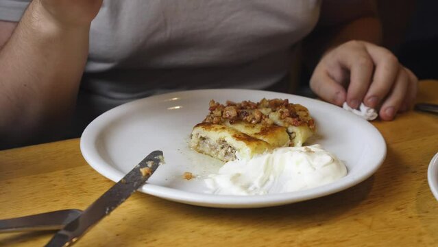 Dinner at the restaurant. A man eats potato pie with sour cream. Close-up.