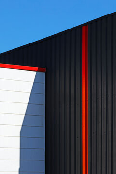 Architecture industrielle noir et couleur en habillage m&eacute;tallique d'un mur de fa&ccedil;ade de b&acirc;timent moderne dans une zone commerciale.