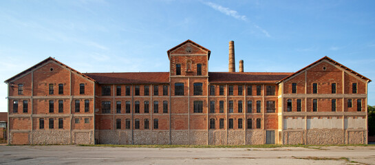Ancienne usine désaffectée en brique rouge avec ses bâtiments symétriques et ses cheminées en...