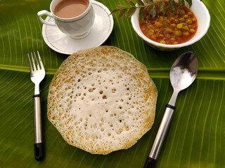 Appam, aappam, Lacy rice flour pancakes. Famous Kerala breakfast served with vegetable curry and tea on banana leaf