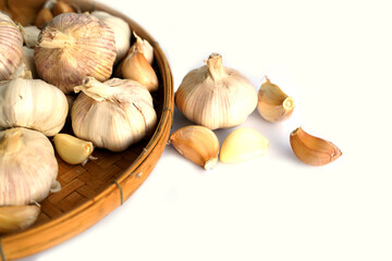 Garlic in a bamboo basket on a white background It is a medicinal plant in Thai kitchens used as an ingredient in food. It has a pungent odor and a spicy taste. It can be eaten both fresh and cooked.