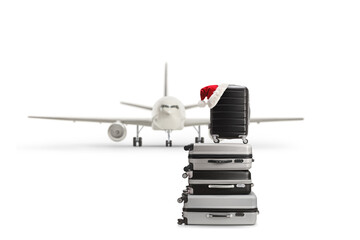 Pile of suitcases with santa hat in front of a plane