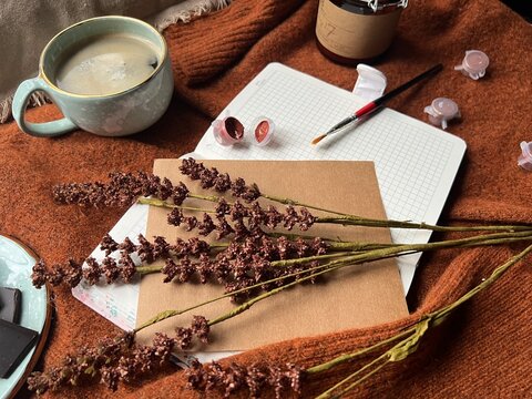 The image shows a notebook, cup of coffee, and flowers on a sweater. 