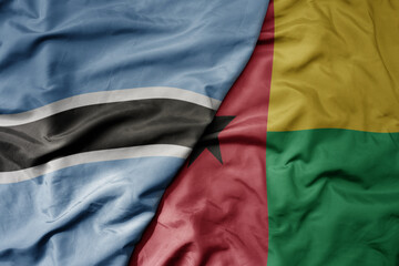 big waving national colorful flag of botswana and national flag of guinea bissau .