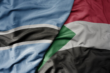 big waving national colorful flag of botswana and national flag of sudan .