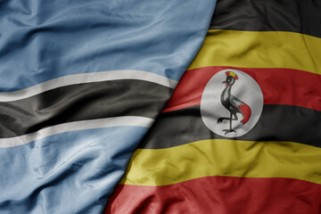 big waving national colorful flag of botswana and national flag of uganda .