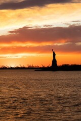 Fototapeta na wymiar Iconic Statue of Liberty silhouetted against the background of a vibrant sky at sunset