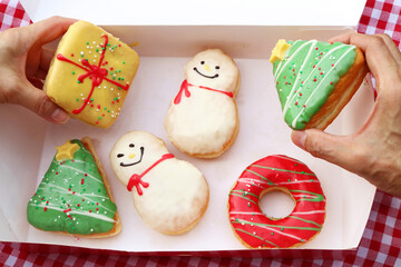 Hands Picking Delectable Christmas Doughnuts from a Box