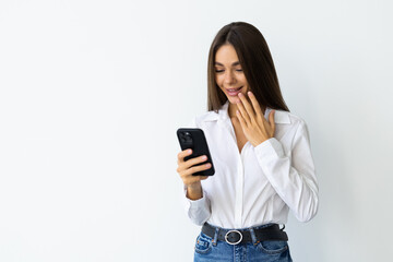 Happy b woman holding smartphone in hands and looking at the camera over white background