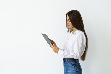 Young woman smiling and holding digital tablet, standing over white background