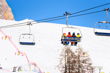 Skiers on a chairlift in an alpine resort on a sunny winter day
