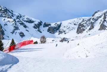 Fotobehang Skiers on a steep ski slope on a sunny winter day © alpegor