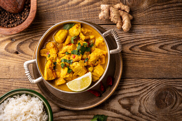 Chicken in curry sauce and rice on wooden background top view, Indian food