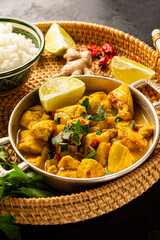Chicken in curry sauce and rice on black background, Indian food vertical photo