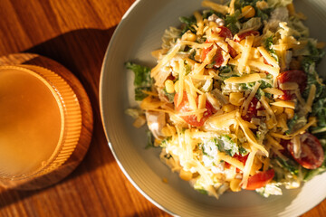 Light breakfast salad on wooden table under sunlight.