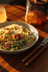 Light breakfast salad with tea on a wooden table under sunlight.