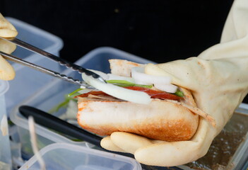 banh mi while preparing, street food Vietnamese sandwich but doing hygiene, short baguette with...