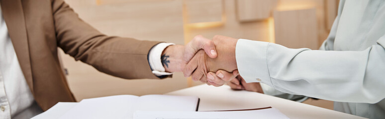 cropped shot of woman shaking hands with middle aged realtor in real estate office, deal banner